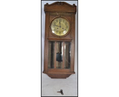 A vintage early 20th century oak cased wall clock having a silvered dial with Arabic numeral chapter ring and faceted hands o