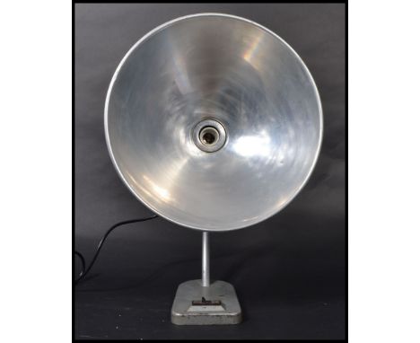 A fantastic mid 20th century desk lamp raised on a cast metal base with a sweeping polished steel arm surmounted with an over