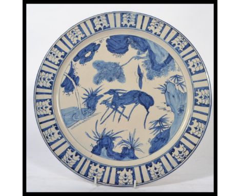 An early 19th century Dutch Delft blue and white charger plate having geometric border with central panel depicting a deer wi