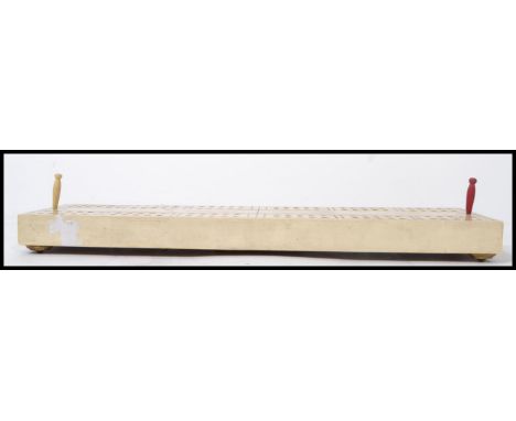 A 19th century Victorian ivorine cribbage board raised on brass feet with opening wooden slot with bone pins. Measures 32 cm 