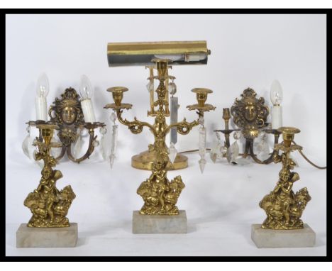 An early 20th century 3 piece garniture of brass and marble candelabra, each adorned with putti to include single and double 