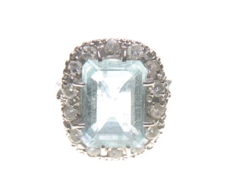 An aquamarine and diamond cluster ring
The central step-cut aquamarine, to an illusion set brilliant-cut diamond surround, mo