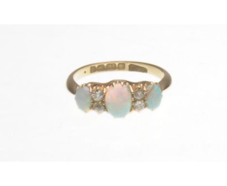 An opal and diamond ring
The three oval cabochon-cut opals interspaced by two old-cut diamonds, to a claw-setting and an 18ct