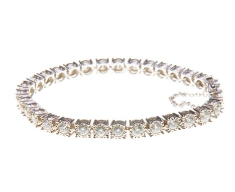 A diamond line bracelet
Composed of a continuous line of brilliant-cut diamonds, to an illusion setting and safety chain, sta