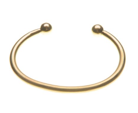A 9ct gold open bangle
Of plain form, terminating in gold spheres, length 8, weight 38g 
