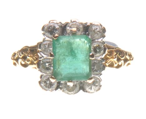 An emerald and diamond cluster ring
Of rectangular form, the central step-cut emerald to a round brilliant-cut diamond surrou