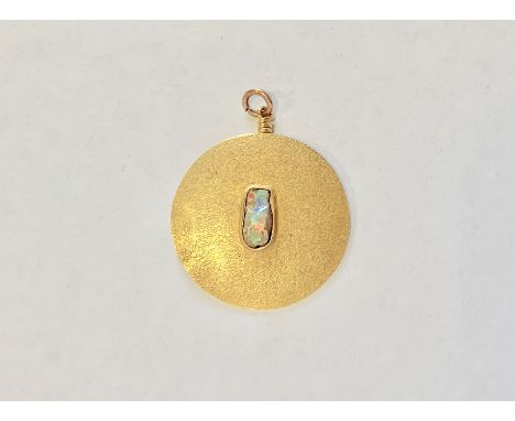 A contemporary high carat yellow metal and raw opal pendant, of discus shape, textured and centrally rub-set with a raw-cut o