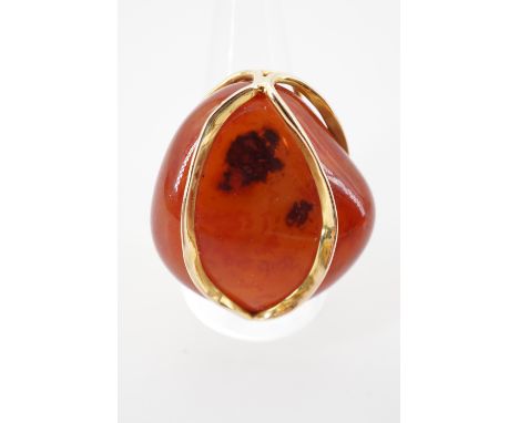 A contemporary high carat yellow metal and carnelian pebble cocktail ring, the carnelian of approximately 3 x 2.8 cm, held ca