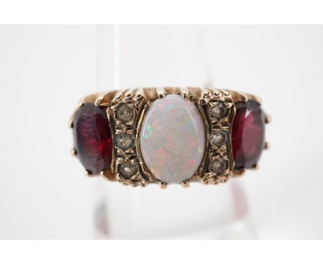 An impressive opal and garnet dress ring, having a central opal cabochon of approximately .78ct, flanked by oval cut garnets,