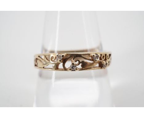 A 9ct gold and diamond band, the ring having a reticulated face depicting scrolling foliage studded with pellet-set brilliant