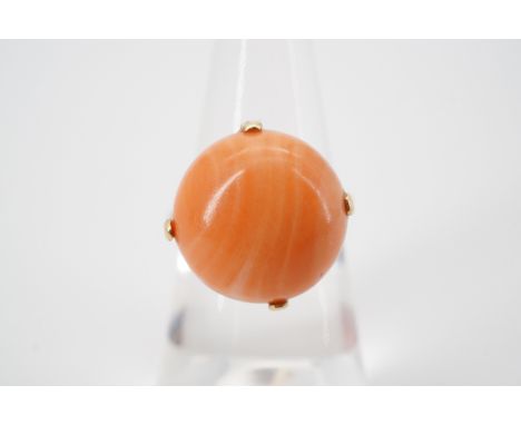 A vintage coral cabochon ring, of circular section, claw-set on a yellow-metal shank, tests as gold, size K, 4.7g