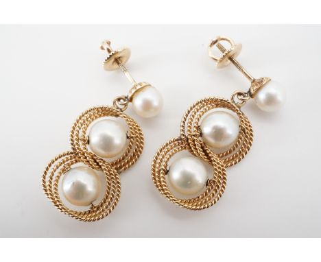 A contemporary pair of pearl and yellow-metal wirework ear pendants, having a pearl stud earring above a wirework knot set wi