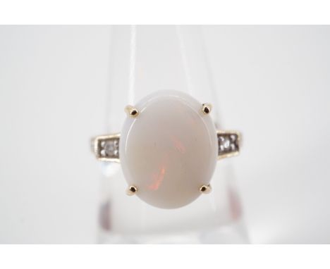 A vintage diamond and opal dress ring, with a central claw-set cabochon opal of approximately 12 x 10 mm, flanked by illusion