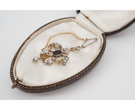 A Belle Epoque Art Nouveau gilt white metal, amethyst-coloured stone and pearl pendant, in an openwork arrangement, having a 