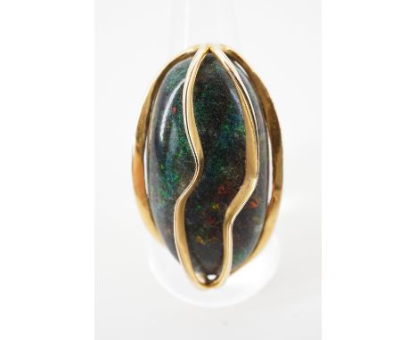 A contemporary high carat yellow metal and black opal cocktail ring, the polished opal of approximately 3 x 1.7 cm, held capt