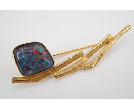 A high carat yellow metal and fire opal brooch, of loosely geometric design, having an opal cabochon of approximately 10 x 12