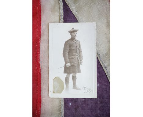 A Great War Union Jack flag together with a period photographic portrait postcard depicting a Scottish soldier in Service Dre