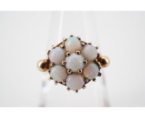 A 1960s 9ct gold opal flower head cluster dress ring, pellet set, and flanked by pelleted shoulders, size I, 2.3g