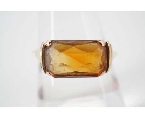 A vintage yellow metal and citrine dress ring, the rectangular citrine being domed and checkerboard cut, claw set and held be