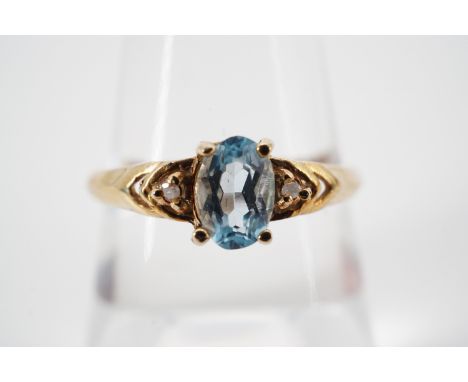 A modern blue topaz dress ring, the oval cut aquamarine of approximately .40ct, pellet-set and flanked by a pair of diamond b