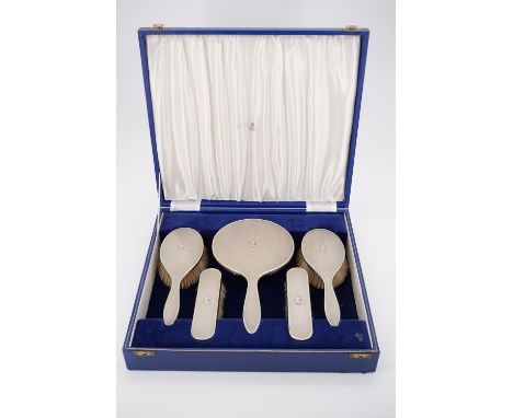 An Elizabeth II silver five piece dressing table brush and mirror set retailed by Hamilton and Inches, with guilloche engrave