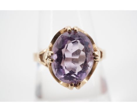 A 9ct gold and amethyst cocktail ring, the oval faceted stone of approximately 2.4ct, claw-set within a cusped petal-form fra