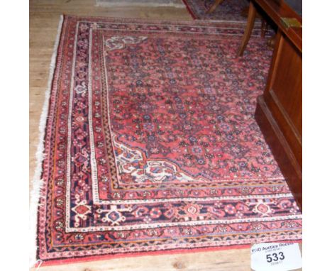 A Middle Eastern style carpet with red ground and geometric border - 310cm x 216cm