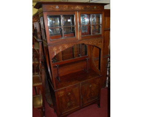 An Art Nouveau Glasgow School style mahogany and inlaid side cabinet, having twin door glazed upper compartment with mirrored