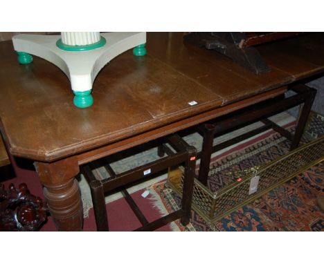 A late Victorian oak extending dining table, having wind-out action and two extra drop-in leaves, raised on ring turned taper