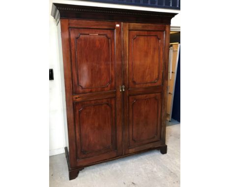 A circa 1900 mahogany two-door wardrobe, the moulded cornice with dentil decoration over two fielded panel cupboard doors enc