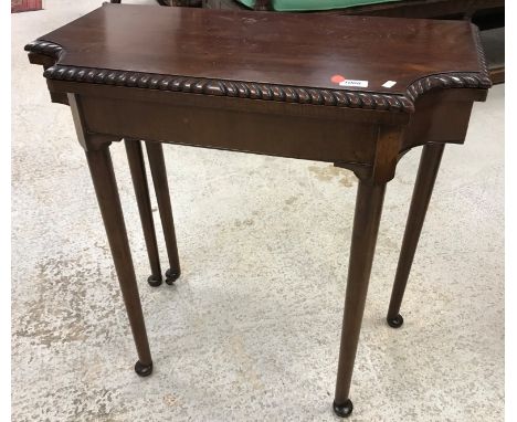 An early 20th Century mahogany fold-over card table, the shaped top raised on turned tapering legs to pad feet, 67 cm wide x 