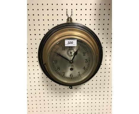A brass cased ship's wall clock by Barkers of Kensington with silvered dial and arabic numerals enclosing a subsiduary second