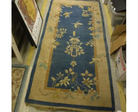 A Chinese carpet, the central panel set with floral motifs on a blue ground, within a stepped blue and pink floral decorated 