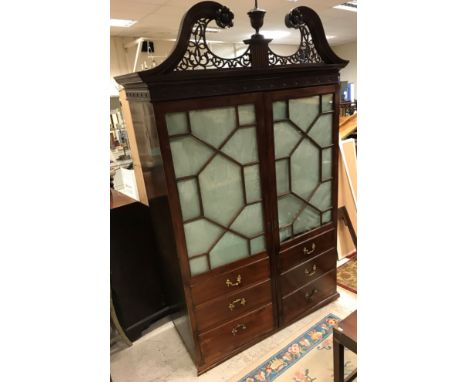 An Edwardian mahogany two-door wardrobe, the fretwork carved broken arch pediment with central vase finial over a medallion d