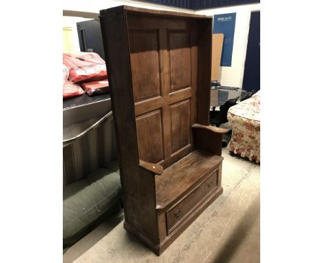 A 19th Century provincial elm bacon settle, the front with four fielded panels and single plank seat over a drawer flanked by