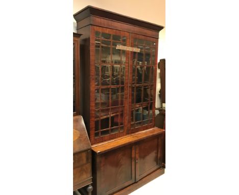 A 19th Century mahogany bookcase cabinet, the upper section with canted cornice over two glazed and barred doors enclosing ad