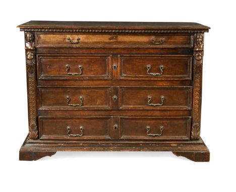 An Italian walnut commode, late 17th century, the rectangular top over four long drawers with carved caryatid pilasters on br