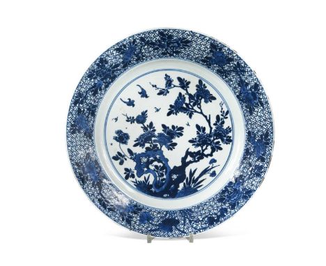 A Chinese blue and white porcelain large plate, Kangxi (1662 - 1722), the central field with a pair of birds amongst peonies 