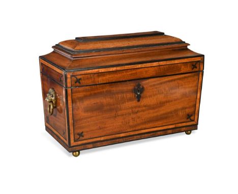 A George III mahogany tea caddy,  of sarcophagus form with ebony stringing and brass lion mask handles, the hinged cover open