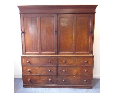 A large mid-19th century oak housekeeper's cupboard; outset cornice above panelled sliding doors and an arrangement of six ha