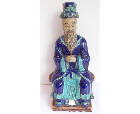 A late 19th/early 20th century Chinese pottery figure glazed in Tang-style; the dignitary seated with hat and long beard upon