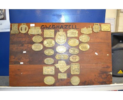 A wooden board mounted with various brass steam engine rally plaques