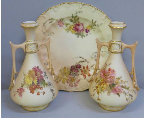 A pair of Royal Worcester blush ivory twin handled vases and tea plate, decorated with sprays of flowers 