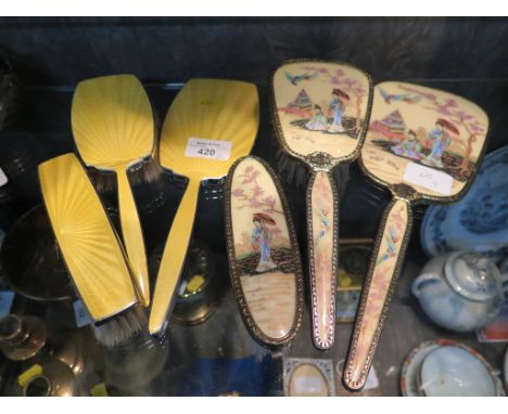 A three piece dressing table set, decorated with yellow enamel, together with a another set decorated with a Japanese lady de