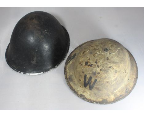 A British Army helmet circa 1982 with replacement liner, together with a Warden's helmet with liner marked '7 Vero I 1938' (2