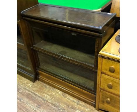 A stained oak two section stacking Globe Wernicke bookcase, raised on shaped plinth, maker's label to the back of each shelf 