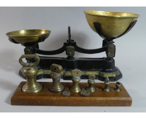 A Pair of Black Painted Kitchen Scales with Brass Pans Together with a Set of Graduated Bell Weights on Wooden Plinth 