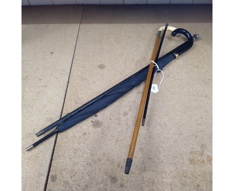 A walking stick with tusk handle and white metal mounts, an umbrella, a walking cane with white metal knob and a small swagge