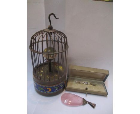 A clockwork clock fashioned as a bird in a cage, a pink stone pendant and a stick pin 