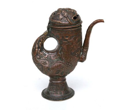 A Tibetan copper water jug or ewer decorated with scrolling stylised dragons with pierced mask cover, 29cms high.